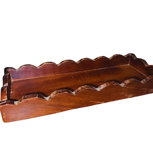 May include: A wooden tray with a scalloped edge. The tray is brown and has a natural wood finish.