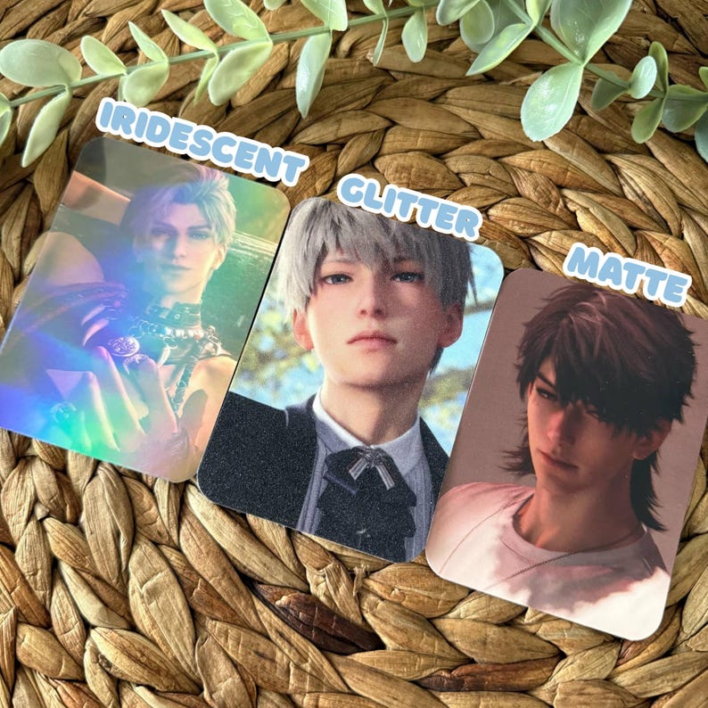 May include: Three rectangular cards featuring anime-style character portraits. The left card has an iridescent finish showing a character with light hair. The middle card has a glitter finish showing a character in a suit. The right card has a matte finish showing a character with dark hair.