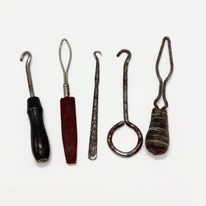 May include: Five vintage metal crochet hooks with wooden handles. The hooks are different sizes and shapes, and the handles are all different colors.