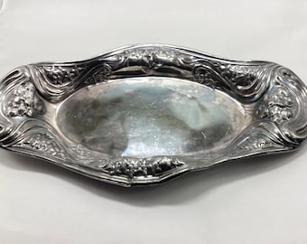 May include: A silver oval serving tray with an ornate design featuring grapes and leaves.