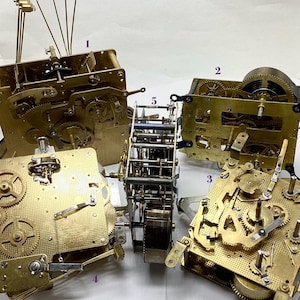 May include: An assortment of vintage clock mechanisms, showcasing intricate brass gears, springs, and levers. The components are arranged on a white surface, highlighting the detailed craftsmanship of the clock parts. The image captures the complexity of the clock's internal workings.