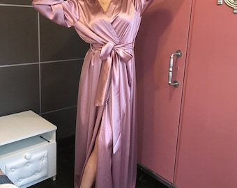 May include: A long, flowing satin robe in a dusty rose colour. The robe has a wrap style with a sash tie at the waist and long sleeves.