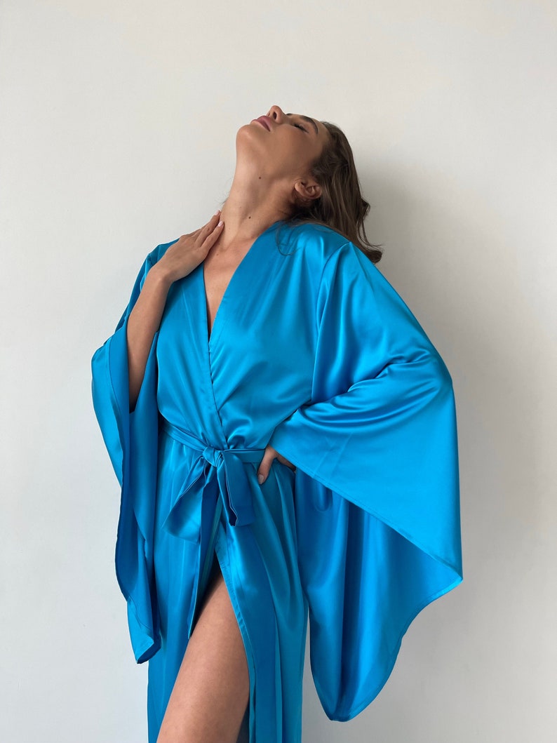 May include: A long, flowing, turquoise blue satin robe with a tie belt and wide sleeves.