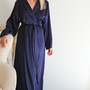May include: A long, navy blue satin robe with a shawl collar and a tie belt.