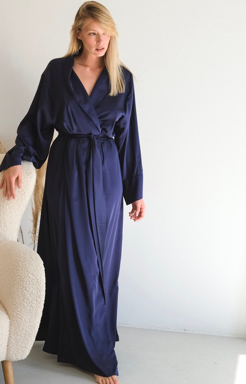 May include: A long, navy blue satin robe with a shawl collar and a tie belt.