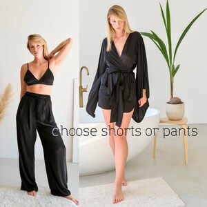 Puede incluir: Dos mujeres con pijamas de sat&eacute;n negro. Una mujer lleva una bata y la otra lleva pantalones. El texto "elige pantalones cortos o pantalones" est&aacute; escrito en la imagen.