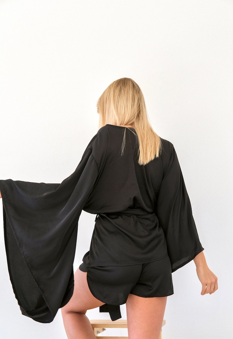 Puede incluir: Una bata de sat&eacute;n negra con mangas largas y anchas y un par de pantalones cortos a juego. La bata se ata a la cintura con una cinta.