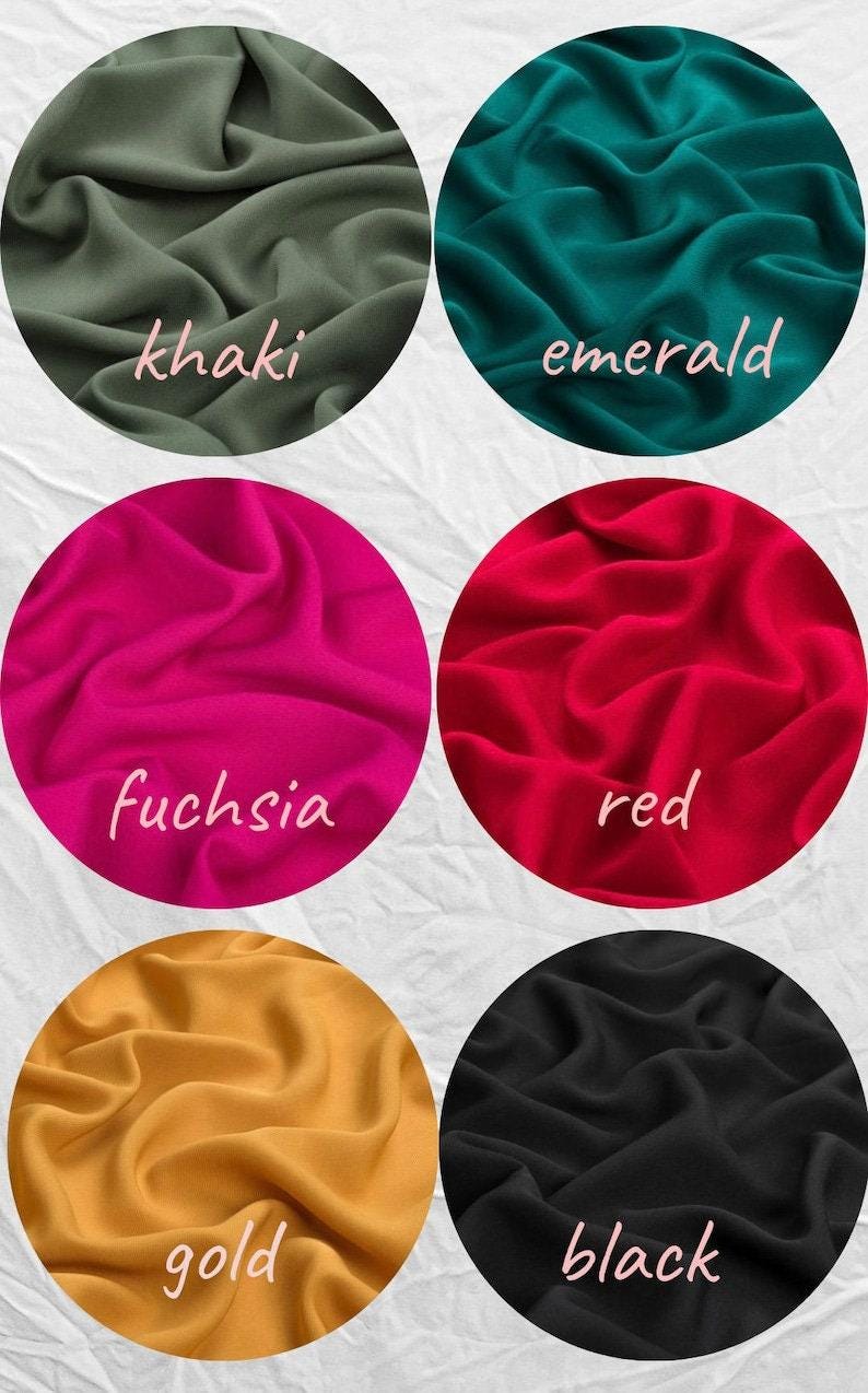 May include: Circular fabric swatches in khaki, emerald, fuchsia, red, gold, and black. Each swatch has a different color and a handwritten label. The fabric is gathered, showing its texture.