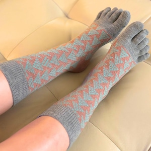 May include: A pair of gray toe socks with a geometric pattern in shades of coral and teal. The socks are designed to separate each toe. The socks are made of a soft, knitted material.