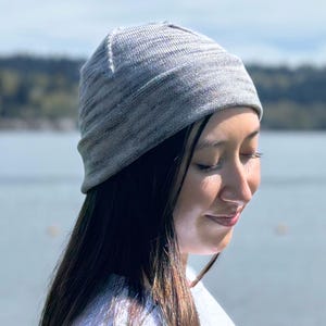 May include: A gray beanie hat with a textured knit pattern. The hat is made of a soft material and is designed to be worn on the head. The beanie is a neutral color and can be worn by anyone.