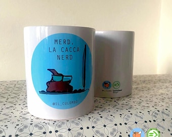 Pode incluir: Caneca de cerâmica branca com um círculo azul com o texto "MERD, LA CACCA NERD" e uma ilustração de desenho animado de uma pilha de cocó usando óculos. A caneca também tem o identificador do Instagram "@IL_CULOMBO".
