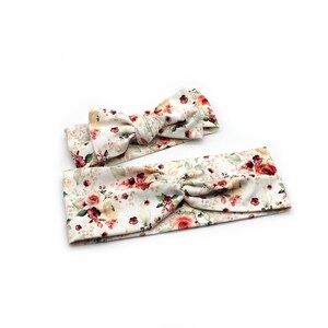May include: Two floral headbands with a white background. One headband is a knotted style, and the other is a bow. The headbands feature a pattern of red, pink, and yellow roses with green leaves. The headbands are made of soft fabric.