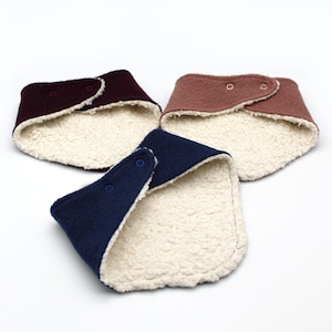 Peut inclure: Trois bavoirs pour bébés de couleur bordeaux, rose poudré et bleu marine. Chaque bavoir a une doublure douce de couleur crème, semblable à de la sherpa. Les bavoirs se ferment avec des boutons-pression. Les bavoirs sont conçus pour être portés autour du cou.