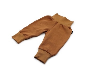 May include: A pair of brown baby pants with ribbed texture. The pants have a high waistband and fitted cuffs at the ankles. The fabric appears soft and comfortable, suitable for infants and toddlers.