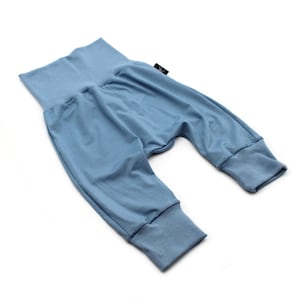 May include: Pale blue baby trousers with a high, folded waistband and ribbed cuffs at the ankles. The soft fabric is a light blue. A small black label is attached to the waistband. These trousers are designed for comfort.