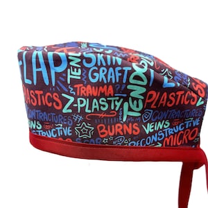 Może przedstawiać: Czerwono-niebieski chirurgiczny czepek z nadrukiem słów "flap", "skin graft", "trauma", "z-plasty", "plastics", "burns", "veins", "constructive" i "micro".