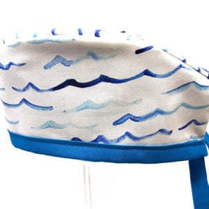 May include: A white scrub cap with a blue watercolor wave pattern and a blue tie.