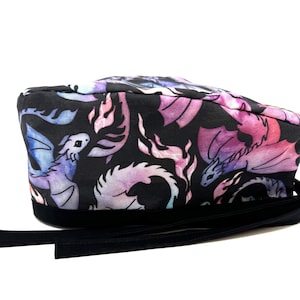 May include: Black scrub hat with a colorful watercolor print of dragons. The hat has a black tie.