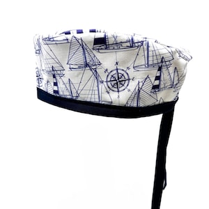 Może przedstawiać: Biały czepek chirurgiczny z granatową lamówką i wzorem żaglówek i kompasu.