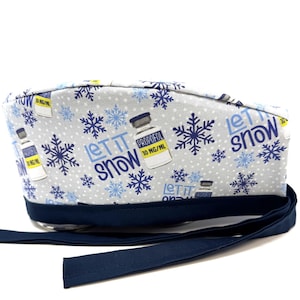 Op de afbeelding: Een blauwe en witte scrub-muts met een winterthema. Het heeft een herhalend patroon van sneeuwvlokken en flesjes met de tekst "Let it snow" en "Propofol 10 mg/ml". De muts heeft een donkerblauwe strop.