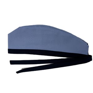 May include: A light blue surgical scrub cap with a black band and long black ties. The cap is made of a soft, durable fabric and is designed to be comfortable for extended wear. The ties allow for an adjustable fit.