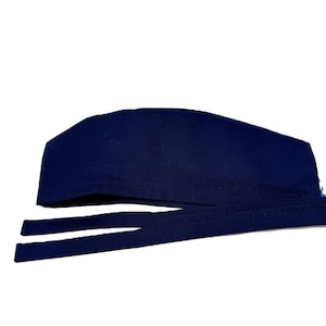 May include: A navy blue surgical scrub cap with long ties. The cap is made of a soft fabric and is designed to be tied at the back of the head. The ties are long and thin, allowing for a secure and adjustable fit.