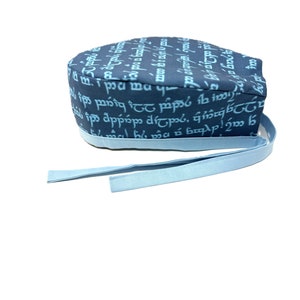 May include: A blue and white surgical scrub hat with a pattern of text in a fantasy language. The hat has a light blue tie.