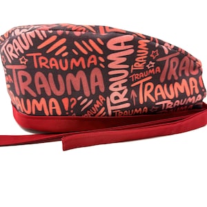 Może przedstawiać: Czerwono-czarny czepek chirurgiczny z powtarzającym się napisem "Trauma" w kolorowym, odręcznym stylu.