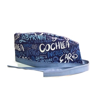 Może przedstawiać: Niebieski chirurgiczny czepek z białym nadrukiem terminów medycznych związanych z uchem, w tym "labirynt", "ślimak", "zawroty głowy", "kowadło" i "półkolisty".