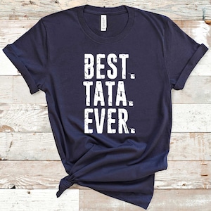 May include: A dark blue t-shirt with the text "BEST TATA EVER" in white distressed lettering.