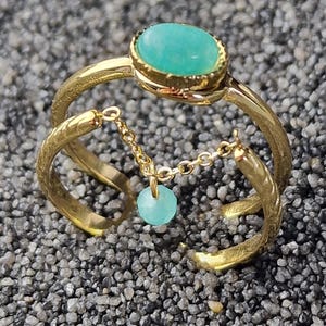 Peut inclure: Une bague en or avec une pierre ovale turquoise et une perle turquoise suspendue à une chaîne.