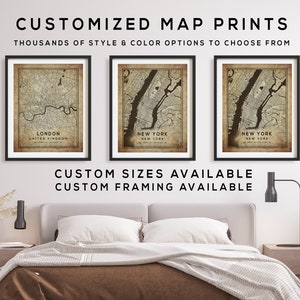 May include: Three framed maps of London, New York City, and New York City. The maps are in a vintage style with a brown background and black text. The frames are black and the maps are hanging on a white wall above a bed with brown bedding. The text below the maps reads "CUSTOM SIZES AVAILABLE CUSTOM FRAMING AVAILABLE".