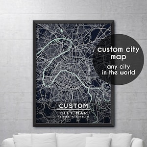 May include: A black framed poster with a detailed map of Paris in blue and white. The poster has the text "CUSTOM CITY MAP" and the coordinates "48.8564 N/2.3481 W". The text "custom city map any city in the world" is in a circle in the upper right corner.