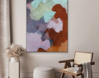 May include: Abstract art painting in a black frame. The artwork uses brushstrokes in shades of brown, purple, blue, and white. The painting is displayed in a room with a neutral colour palette, a wooden chair, and a decorative plant.
