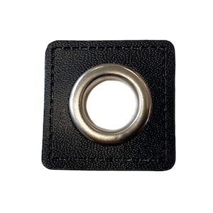 Könnte beinhalten: Ein schwarzer quadratischer Öse mit einem silbernen Metallring. Die Öse ist mit einem dekorativen Stich um den Rand genäht.