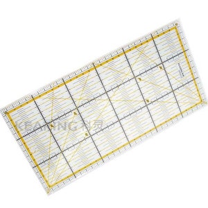Può includere: Un righello in plastica trasparente con segni gialli. Il righello ha un motivo a griglia con linee dritte e linee diagonali. Il righello è lungo 30,5 cm.