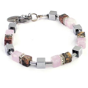 May include: A silver bracelet with alternating pink and brown square beads. The beads are made of hematite and rose quartz.
