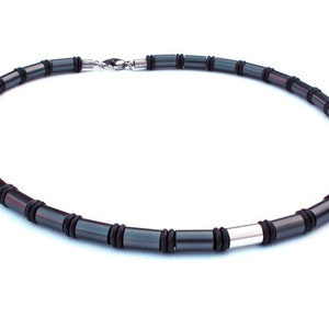 Könnte beinhalten: Eine schwarze Halskette mit silbernen Akzenten. Die Halskette besteht aus runden Perlen, die durch ein Gummiband verbunden sind.