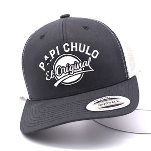 May include: A black and white trucker hat with the text "PAPI CHULO El Original" in white. The hat has a curved brim and a mesh back. The hat is a snapback style.