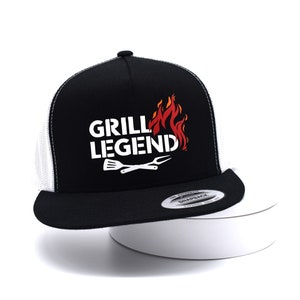 May include: Black and white trucker hat with a white "Grill Legend" text and a red and orange flame graphic. The hat has a white mesh back.