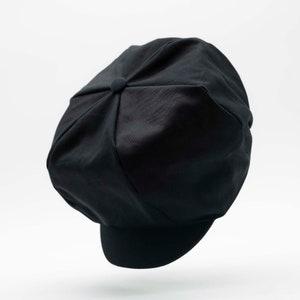 May include: A black newsboy cap with a rounded crown and a flat brim.