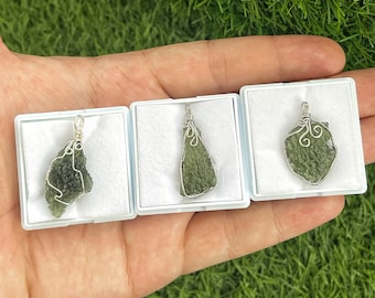 May include: Three green gemstone pendants in small white boxes. Each pendant is wrapped in silver wire and has a unique shape.