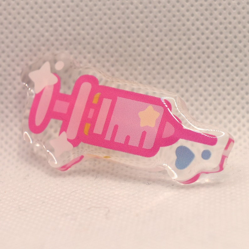 May include: A pink and white syringe with a star on the side, made of clear acrylic.