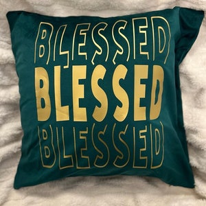 May include: A green velvet cushion with the word "Blessed" repeated three times in gold lettering.