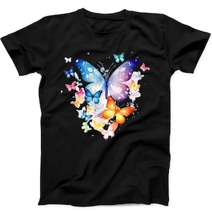 Puede incluir: Una camiseta negra de manga corta con un estampado gráfico central de varias mariposas de diferentes tamaños y colores, incluyendo azul, morado, naranja, rosa y amarillo, dispuestas en un grupo con salpicaduras de pintura estilo acuarela.