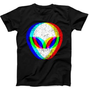 May include: A black short-sleeve t-shirt featuring a central graphic of an alien head. The design has a distressed, weathered texture and utilizes a vibrant, multi-colored chromatic aberration effect with overlapping layers of red, blue, and yellow.