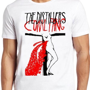 May include: A white short-sleeved t-shirt featuring a graphic print with the text THE DISTILLERS and COMLTING in black and red. The design includes a black cross and a stylised figure with a large red splash pattern extending from the centre.