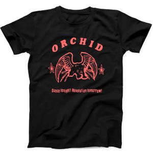 May include: A black short-sleeved t-shirt featuring a coral-coloured graphic of a winged panther centred on the chest. Above the panther is the word ORCHID, flanked by two stars. Below the graphic is the text Dance tonight! Revolution tomorrow!