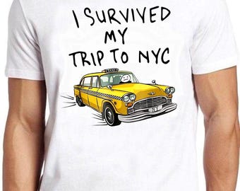 May include: A white short-sleeve t-shirt featuring the black text I SURVIVED MY TRIP TO NYC above a cartoon illustration of a yellow taxi cab with a simple stick figure driver and a checkered stripe along the side of the vehicle body.