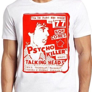 May include: A white short-sleeved t-shirt featuring a red graphic print of a Talking Heads concert advertisement. The design includes a profile illustration, the text "Psycho Killer," "Talking Heads," and "From the people who brought you 77."